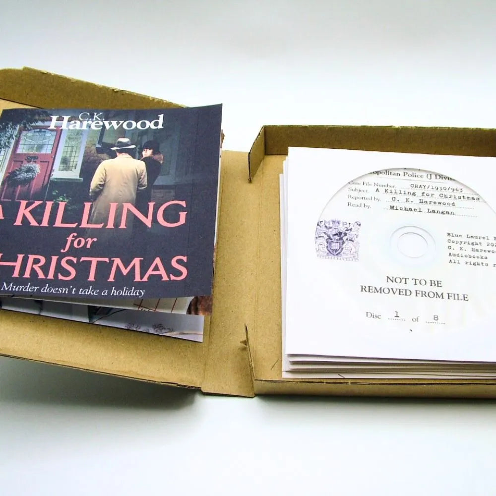 Book titled 'A Killing for Christmas' by C.K. Harewood in an open box with a document inside.