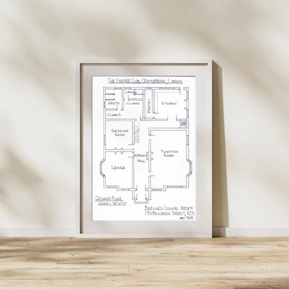 Framed floor plan on a wooden surface with a neutral background
