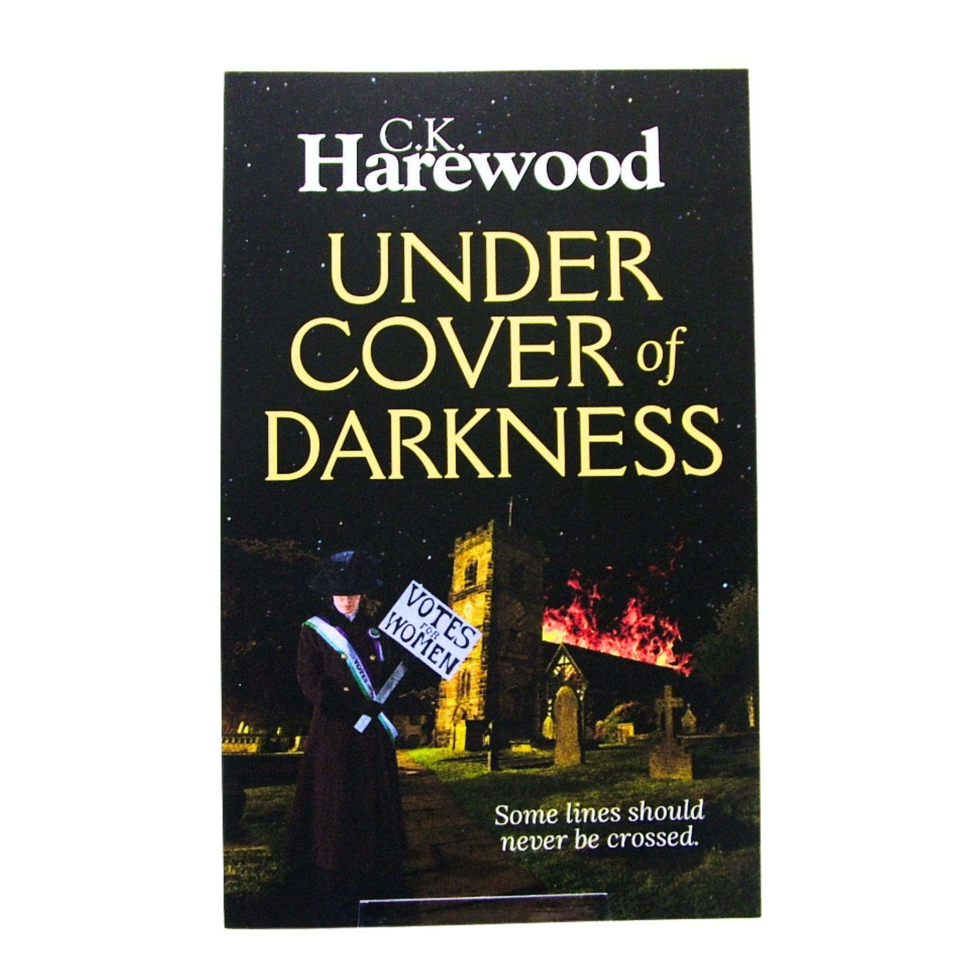 Book cover of 'Under Cover of Darkness' by C.K. Harewood with a Suffragette holding a sign saying Votes for Women against a church on fire.